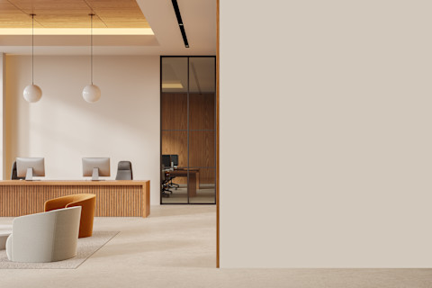 Moderne kantoorruimte met beige armstoelen op een vloerkleed en glazen tussenwand, sfeervol ingericht met warme verlichting.