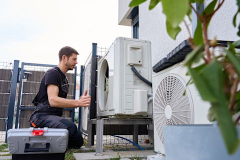 Technicus voert onderhoud uit aan een buitenunit van een warmtepomp bij een woning