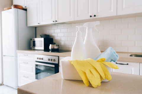 Schoonmaakmiddelen en handschoenen op het keukenblad, klaar om de oppervlakte voor wrappen te reinigen.
