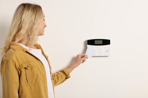 Vrouw bedient een alarmsysteem met een toetsenbord in een moderne woning.