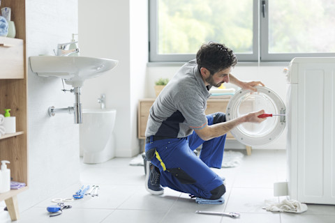 Monteur voert een reparatie uit aan de binnenkant van een wasmachine.