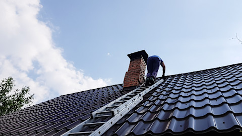 Man klimt de metalen ladder op naar het dak voor dak onderhoud