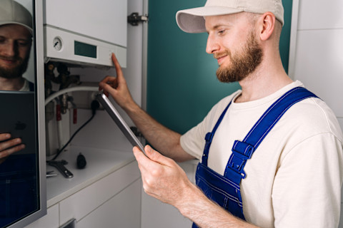 Monteur inspecteert geopende cv ketel tijdens reparatie aan de muur