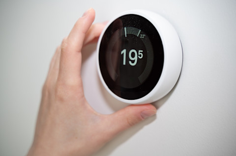  Iemand stelt een slimme thermostaat in, als voorbeeld van slimme warmte- en energiecontrole