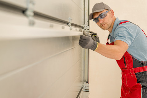 Monteur plaatst nieuwe sectionaal garagedeur in een moderne woning, halverwege de installatie.