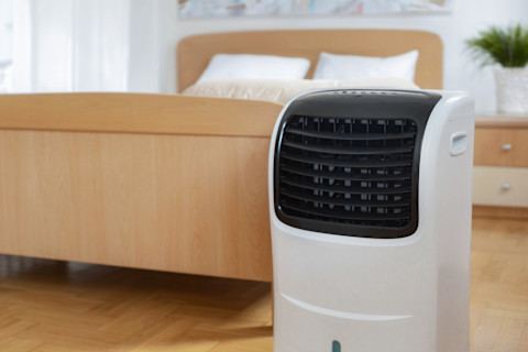 Mobiele airco-unit in een slaapkamer die koele lucht uitblaast.