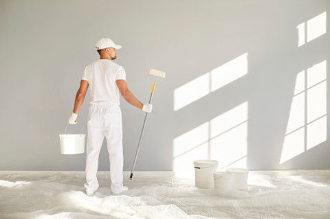 Schilder aan het werk tijdens woningrenovatie, bezig met het verven van een binnenmuur.