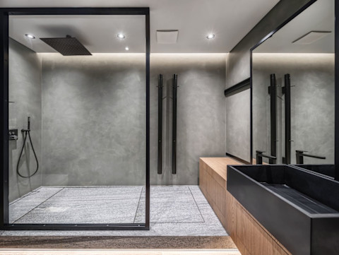 Moderne badkamer met grijze betegelde muren en een glazen douchewand. 