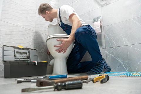 een vakman plaatst een nieuwe wc pot tijdens een toilet renovatie
