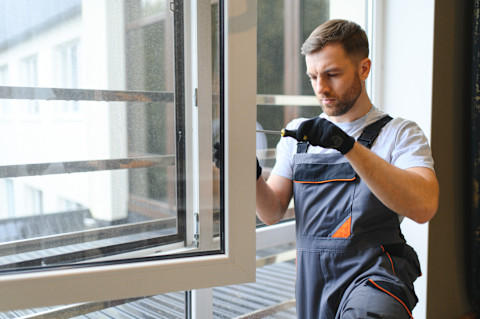 Monteur plaatst een nieuw raamkozijn in een buitenmuur van een woning