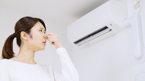 Vrouw houdt haar neus dicht vanwege de airco die stinkt in de kamer
