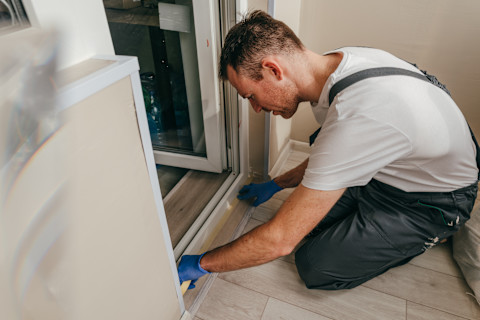 Monteur hangt binnendeur af met behulp van professioneel gereedschap, in een net afgewerkte ruimte