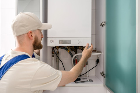 Cv installateur inspecteert een cv ketel tijdens een onderhoudsbeurt.