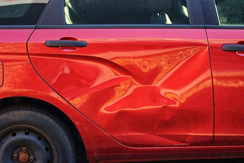 Deur van een rode auto heeft een deur als gevolg van een aanrijding