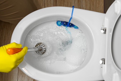  Loodgieter die een verstopte en overstroomde wc schoonmaakt.