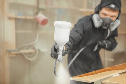 schilder in beschermende kleding spuit een meubel een andere kleur