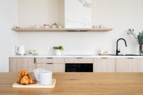 Ontbijt op een houten keukenblad met twee mokken en croissants, sfeervol gedekte keuken.