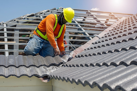 Dakspecialist is bezig met het vervangen van een dak met een nieuwe houten constructie en dakpannen