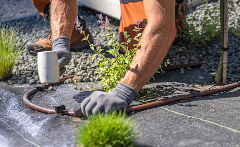 Hovenier verbindt onderdelen van een irrigatiesysteem tijdens de aanleg van tuin drainage.