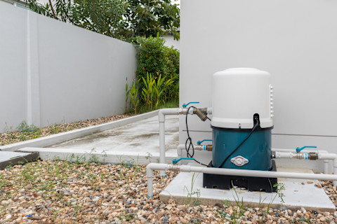 elektrische waterpomp buiten een wit gebouw
