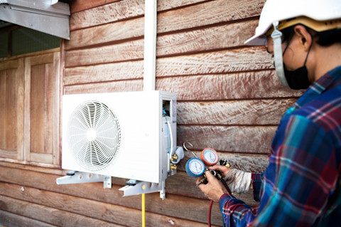 Airco specialist checkt de airco van een huis om te bepalen of deze bijgevuld moet worden.