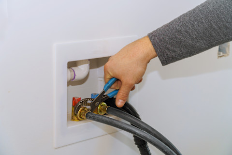 Wateraanvoerslang wordt aangesloten op een wasmachine, close-up van installatieproces.