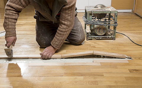 vakman werkt aan de reparatie van een lichte houten vloer