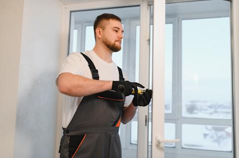Monteur plaatst nieuw raamkozijn in bakstenen muur van woning