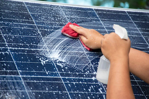 Mini-zonnepaneel wordt schoongespoten met water tijdens het schoonmaken.