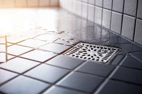 Water stroomt naar beneden door een strak afvoervierkant in de douche, symbool van hygiëne en goede doorstroming.