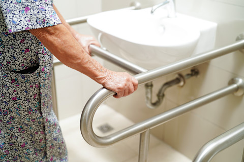Oudere vrouw gebruikt een handgreep in de badkamer voor extra veiligheid
