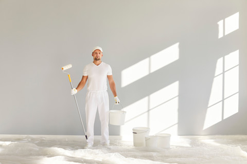 Schilder verft een muur met een roller in een modern appartement