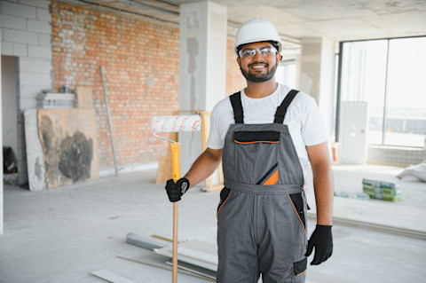 Schilder aan het werk op een muur, bezig met professioneel binnenschilderwerk.