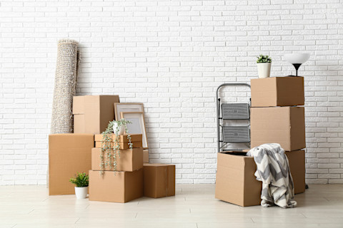 Verhuisdozen staan klaar tegen een witte muur voor een georganiseerde verhuizing.