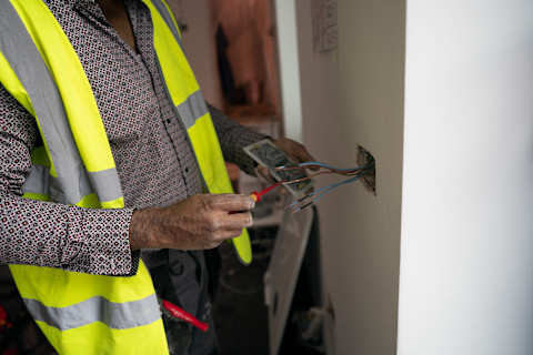 Elektricien werkt aan de bedrading in huis voor het plaatsen van een laadpaal thuis