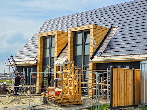 Nieuwbouwwijk in aanbouw met prefab elementen in typisch Nederlandse buitenwijk, overzicht bouwplaats.