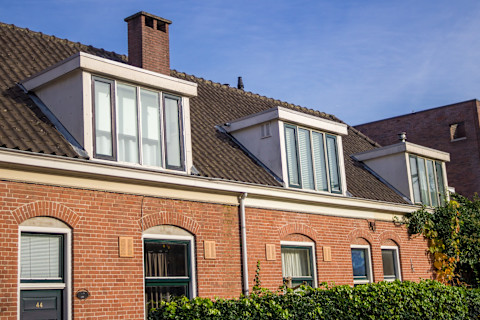 Traditionele woning met een houten dakkapel voorzien van ramen en dakpannen.