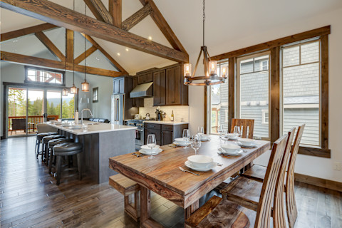 Eetkamer naast een rustieke moderne keuken met houten plafondbalken en industriële elementen.