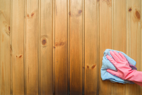 Hand in rubberen handschoen veegt roetvlekken van een witte muur als gevolg van rooklekkage.