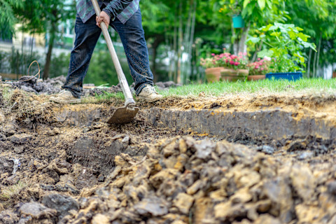 vakman verwijderd grond en grasmat uit een tuin met professioneel gereedschap