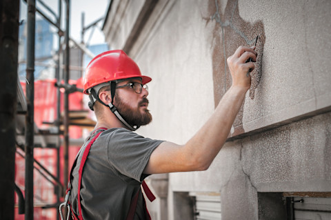 Bouwvakker installeert styrofoam isolatieplaten op een buitenmuur tijdens gevelrenovatie.