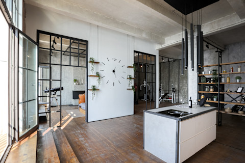 Lichte loftstudio met open keuken, betonnen muren en minimalistische inrichting.