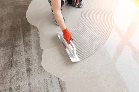 Nieuwe cementdekvloer wordt gelijkmatig geëgaliseerd met een betonnen afwerkmachine.