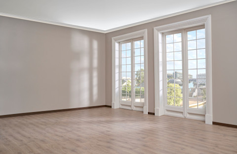 Een leeg huis woonkamer met grote witte ramen en een parket vloer