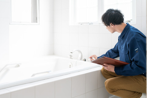 Vakman inspecteert bad en waterleidingen in badkamer.