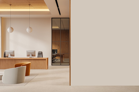 Moderne kantoorruimte met beige armstoelen op een vloerkleed en glazen tussenwand, sfeervol ingericht met warme verlichting.