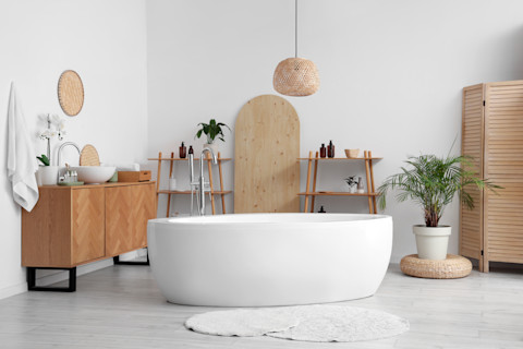 Een witte badtub in een open ruimte met houten accessoires in de badkamer