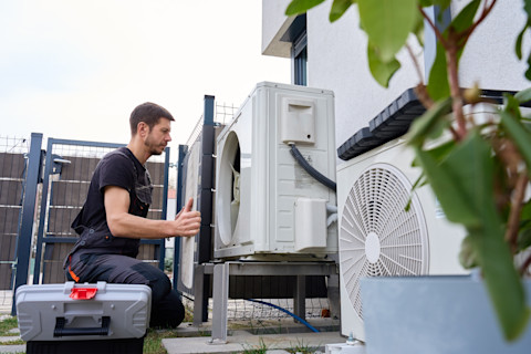 Technicus voert onderhoud uit aan een buitenunit van een warmtepomp bij een woning