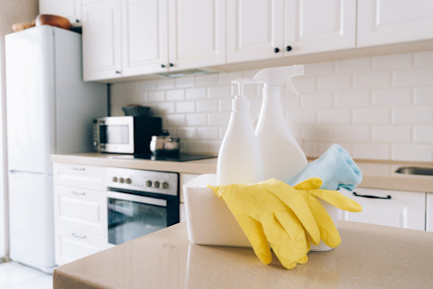 Schoonmaakmiddelen en handschoenen op het keukenblad, klaar om de oppervlakte voor wrappen te reinigen.