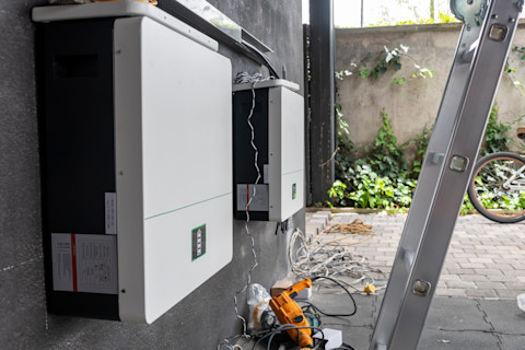 Installateur sluit een thuisbatterij en laadinstallatie aan bij een woning met zonnepanelen.
